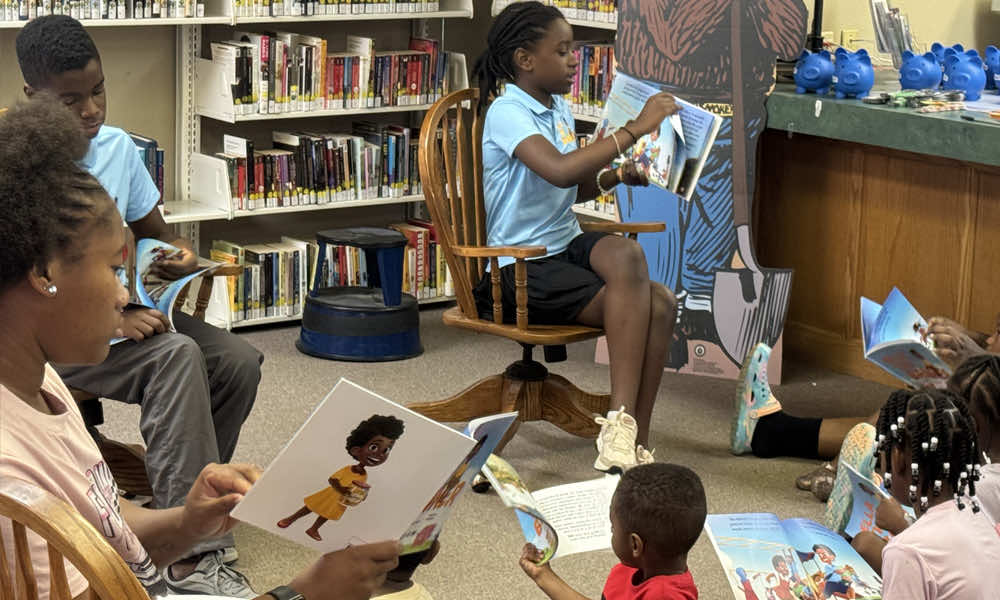 Student reading a book to the class